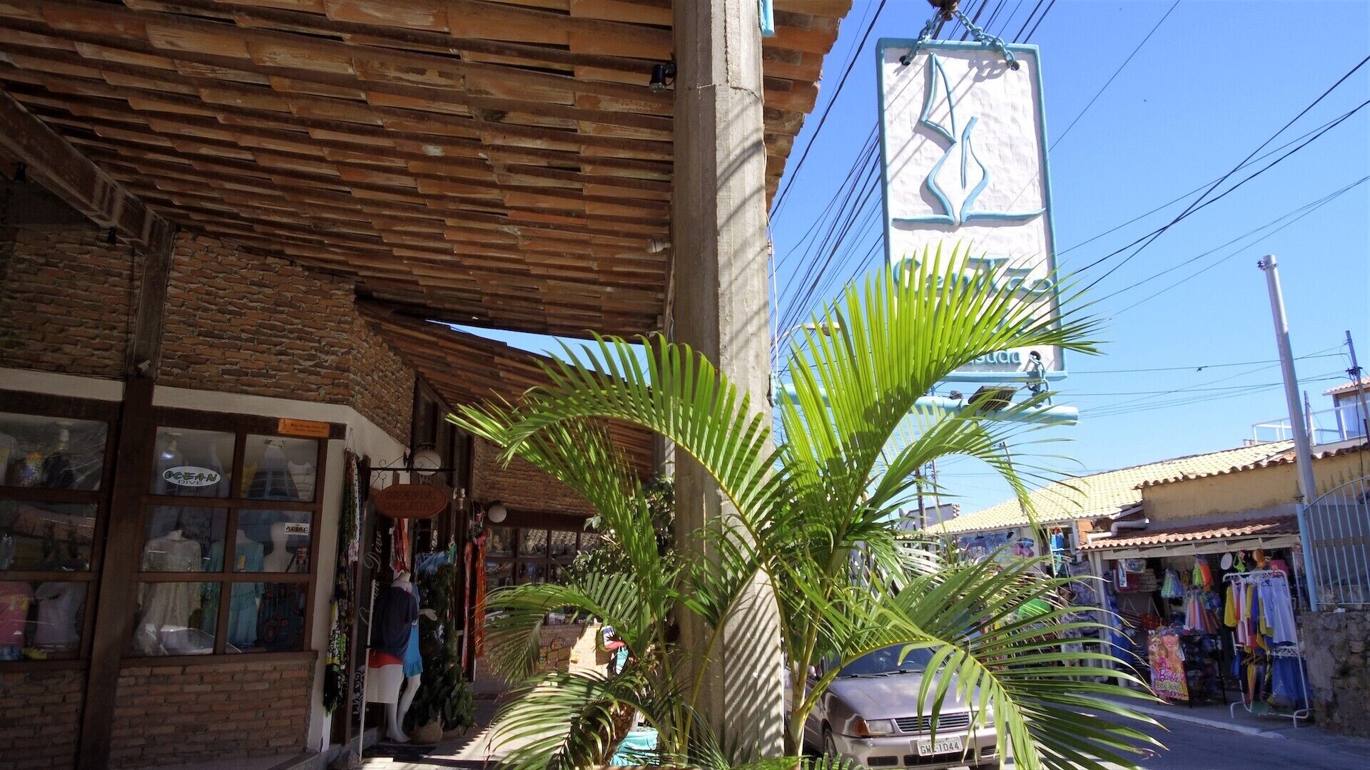 A street view with a shop on the left and a car parked on the right.
