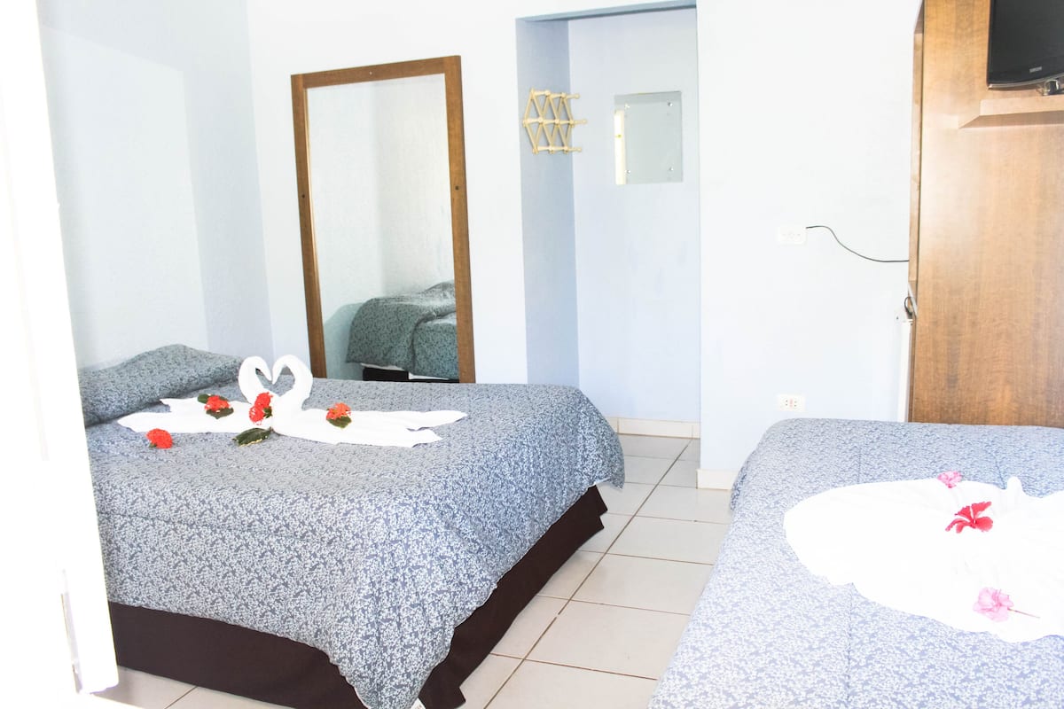 Ein Hotelzimmer mit zwei Betten, einem großen Spiegel und einer Holztür.