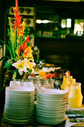 A table set with stacked plates, a floral centerpiece, and a pitcher of yellow beverage.