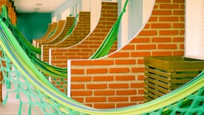 A series of hammocks hanging in a row against a brick wall.