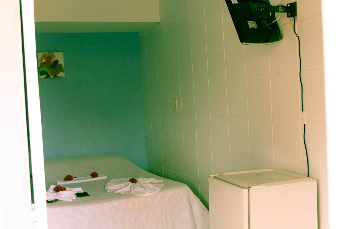 Ein kleines Zimmer mit einem Einzelbett, einem weißen Heizkörper und einer grünen Wand.