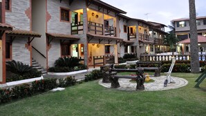 A multi-story hotel with a stone facade, balconies, and a landscaped garden with sculptures and a fountain. - Pousada Porto Familly (Ipojuca)