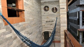 A hammock in a room with a tiled floor, a small window, and a wall-mounted rack. - Pousada Porto Familly (Ipojuca)