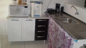 A compact kitchen with a microwave, coffee maker, and a sink. - Hostel Guerreiro (Maceió)