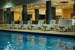 Una piscina al aire libre, sillones reclinables de piscina
