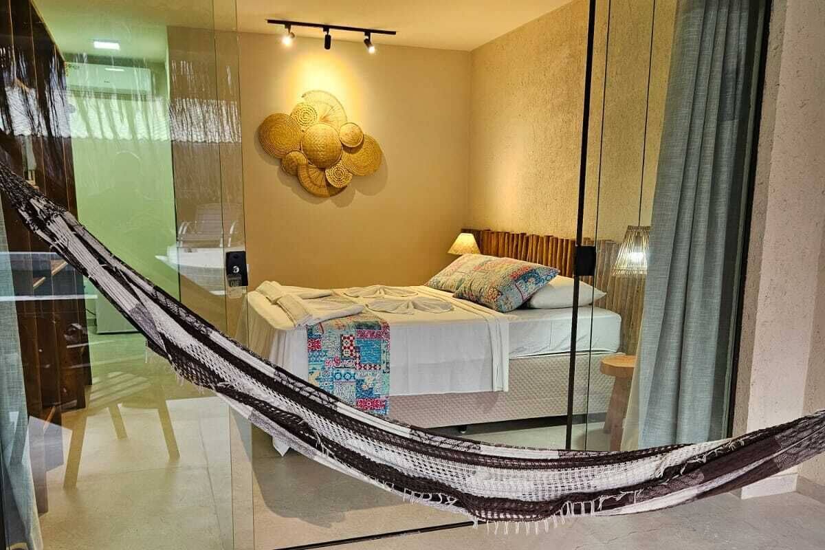 Habitación de hotel moderna con una cama grande, una hamaca y vistas del interior a través de un muro de cristal.