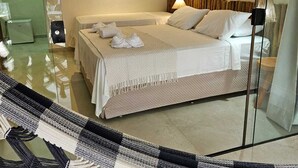 A modern hotel room with a large bed, a wall-mounted decorative light fixture, and a glass partition reflecting the room. - Pousada Sempre Graciosa (Marechal Deodoro)