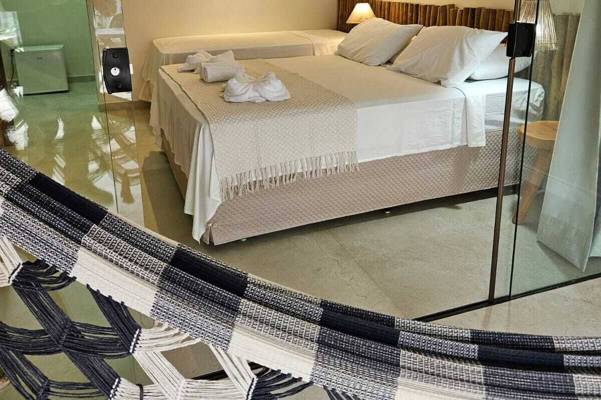 Una habitación de hotel moderna con una cama grande, una lámpara decorativa fijada a la pared y un panel de vidrio que refleja la habitación.