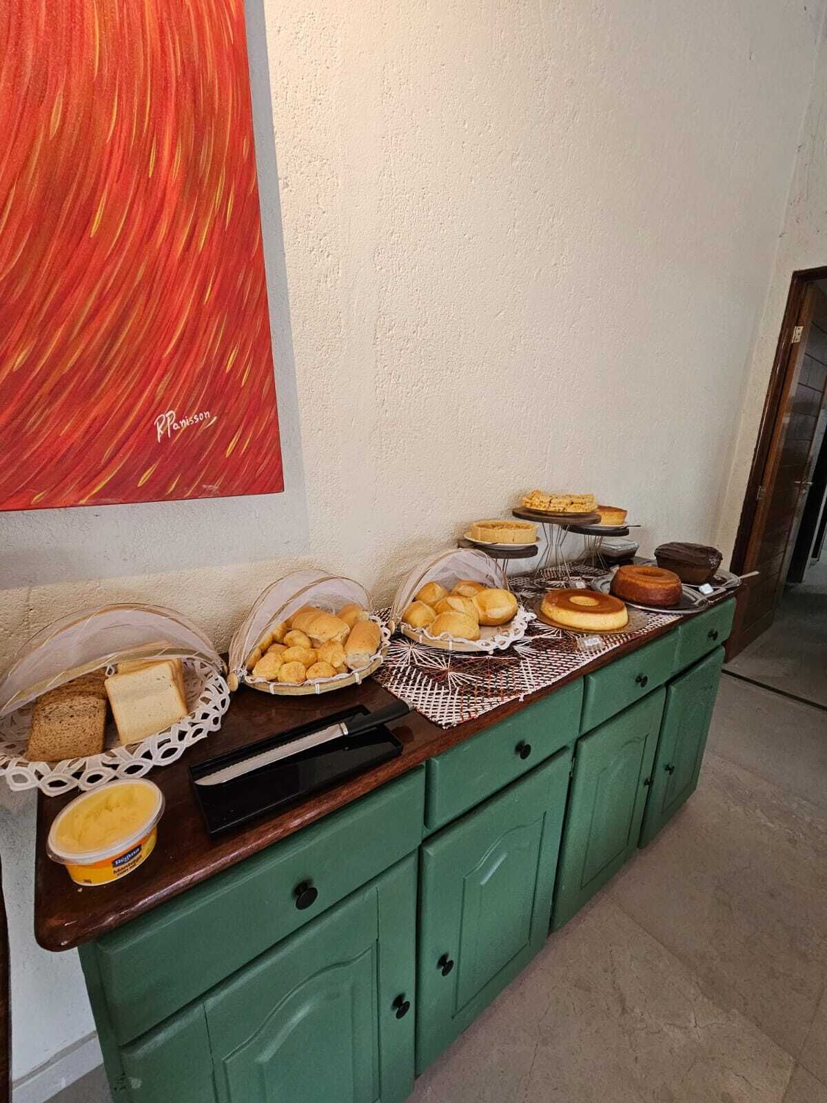 Een buffetopstelling met diverse broden, gebak en een botervloot op een groene toonbank.