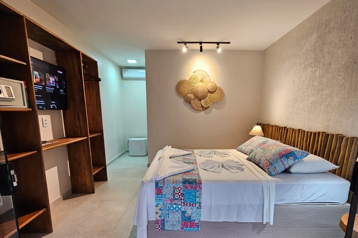 A modern bedroom with a bed, a wooden wardrobe, and a wall-mounted light fixture.