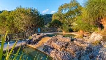 Una piscina al aire libre, sombrillas, sillones reclinables de piscina