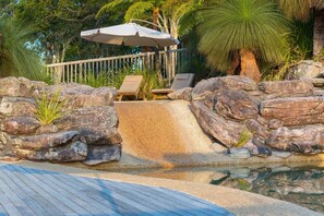 Una piscina al aire libre, sombrillas, tumbonas