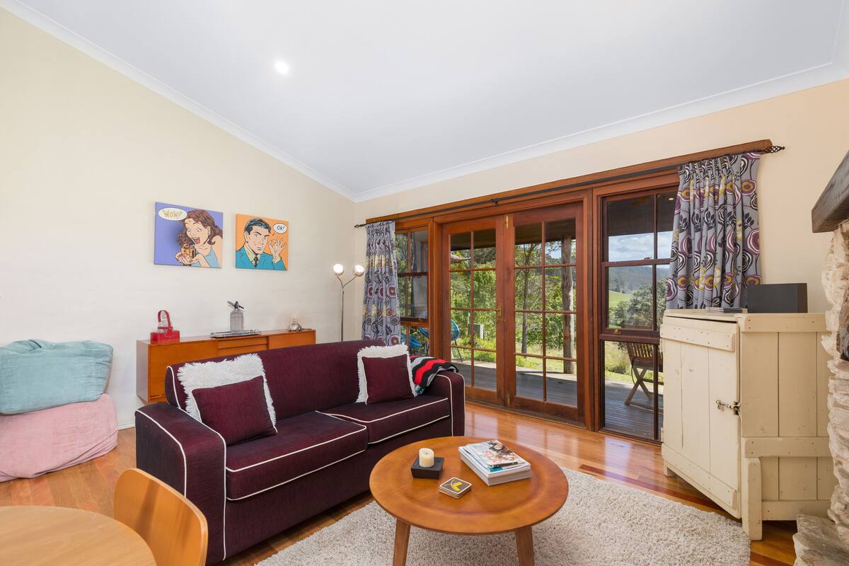 A living room with a sofa, coffee table, and a view through a glass door to the outdoors.