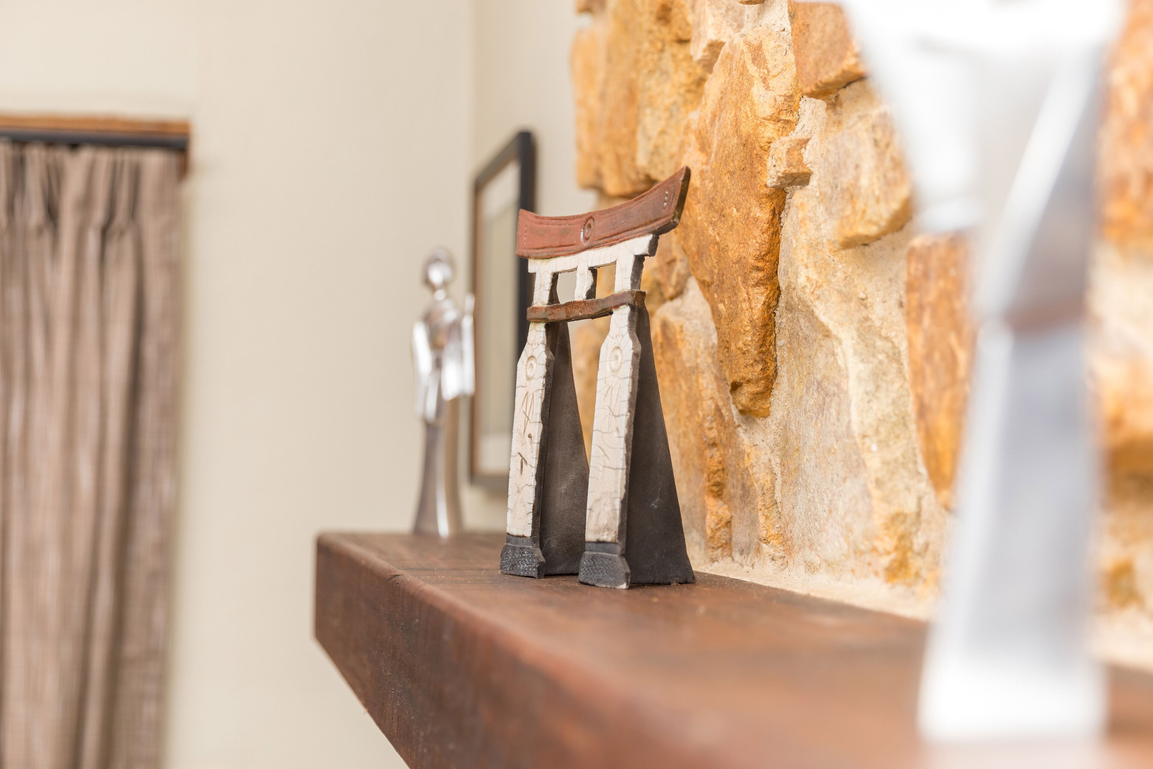 A rustic wooden chair with a metal frame on a wooden shelf against a stone wall.