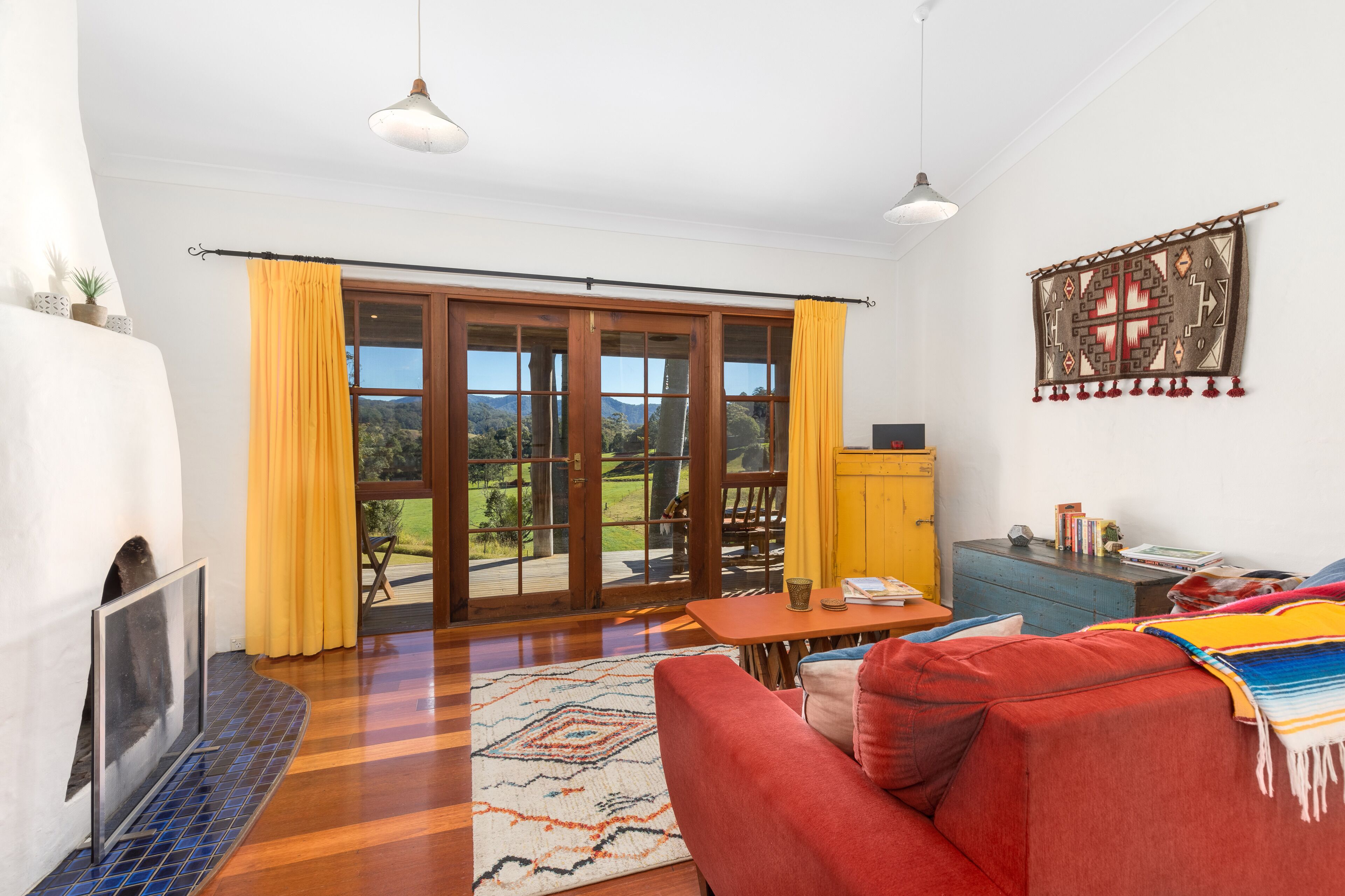 Una sala de estar con chimenea, un sofá, una mesa de centro y vistas a una terraza a través de un ventanal corredizo.