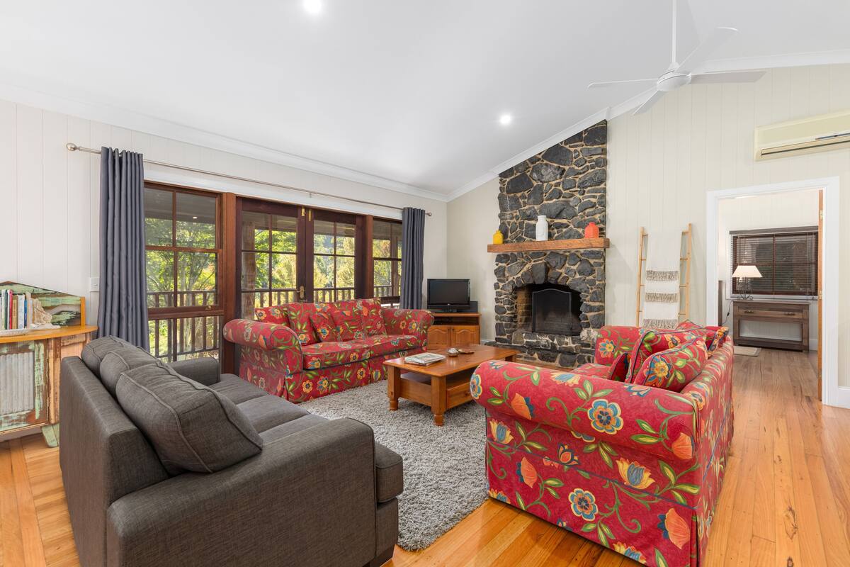A living room with a fireplace, a sofa set, a television, and a stone wall.