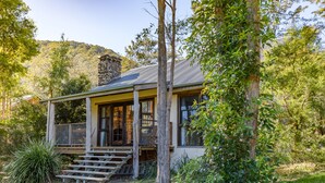 Une maison avec un porche, des marches en bois et une cheminée en pierre.