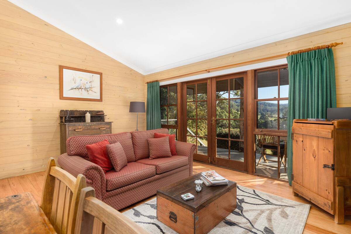 A cozy living room with a patterned sofa, a wooden coffee table, and a view through large sliding glass doors.