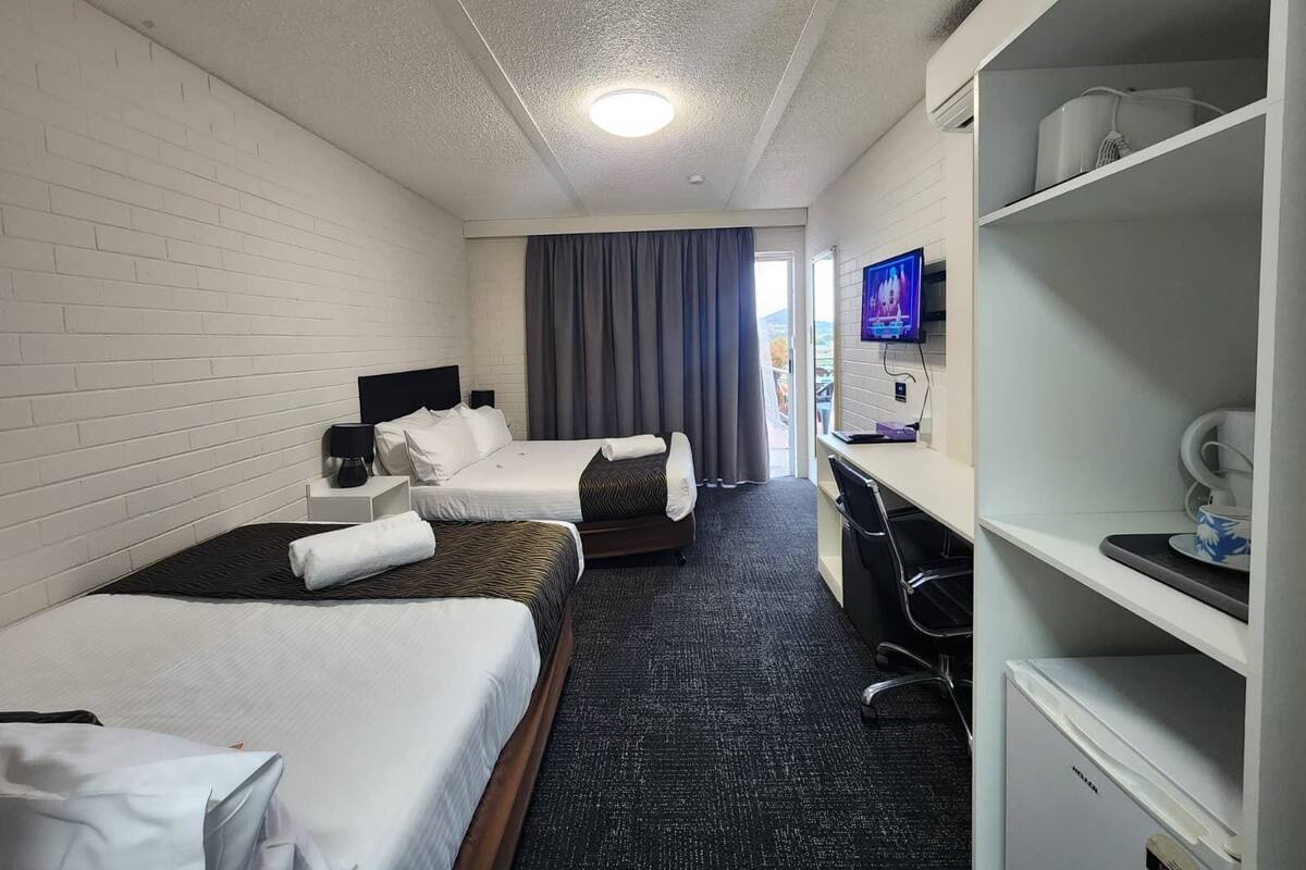 Habitación de hotel con dos camas, un escritorio, televisión y un minibar.