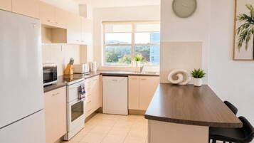 A modern kitchen with white cabinets, a wooden countertop, and a view of the outdoors through a window.