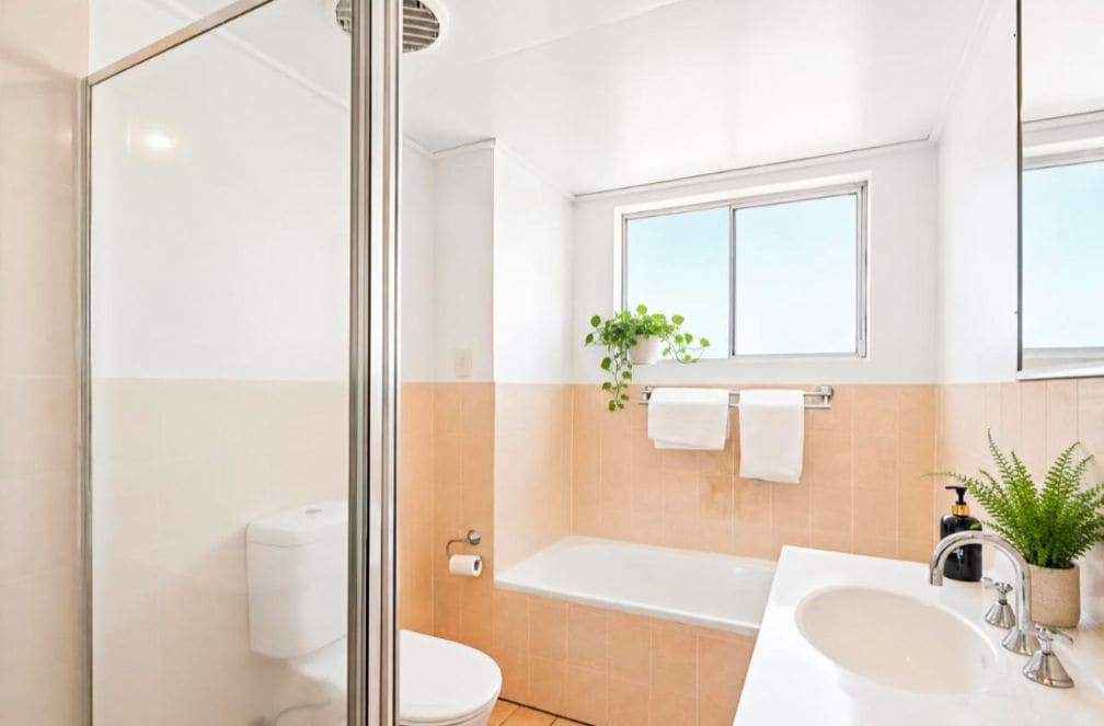 Een moderne badkamer met een glazen douchecabine, een bad, een toilet en een wastafel met spiegel.