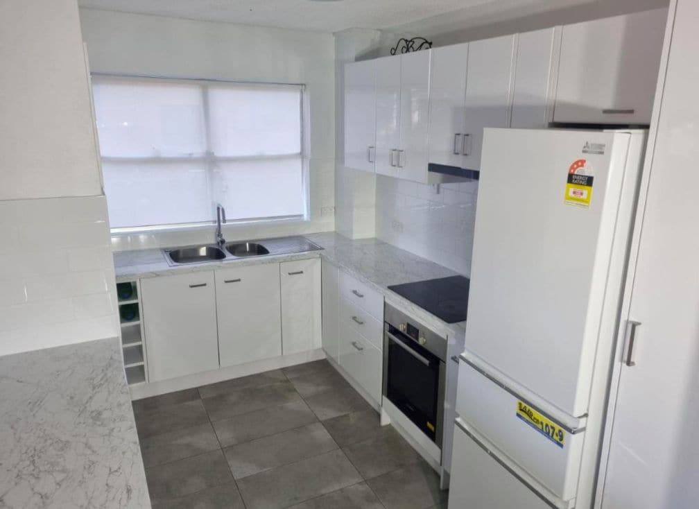 A kitchen with white cabinets, a sink, a stove, and a refrigerator.