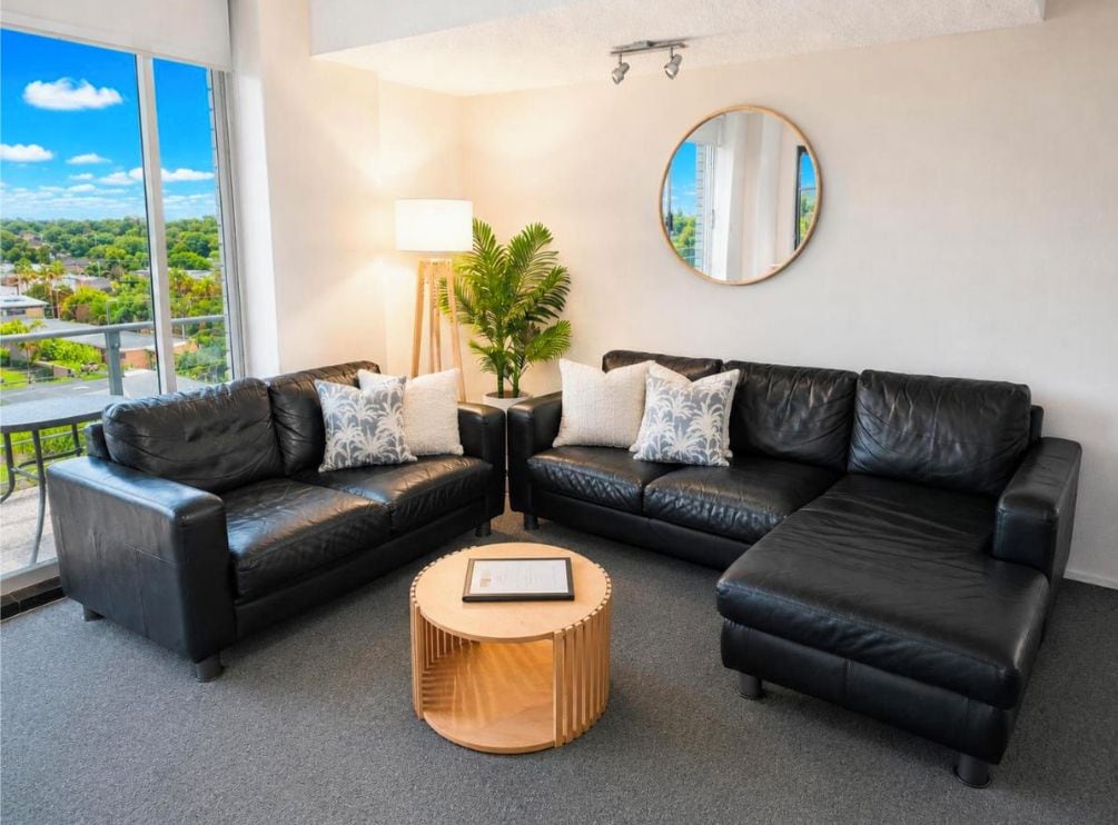 A modern living room with a sectional sofa, a round coffee table, and a potted plant.