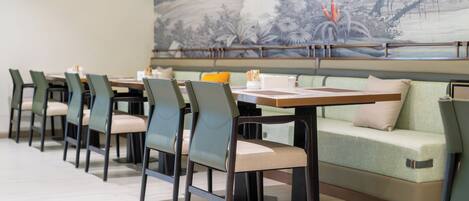 A restaurant with a long table, chairs, and a sofa.