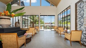 Amplo espaço interno com móveis de vime, grandes janelas e vista para o exterior.