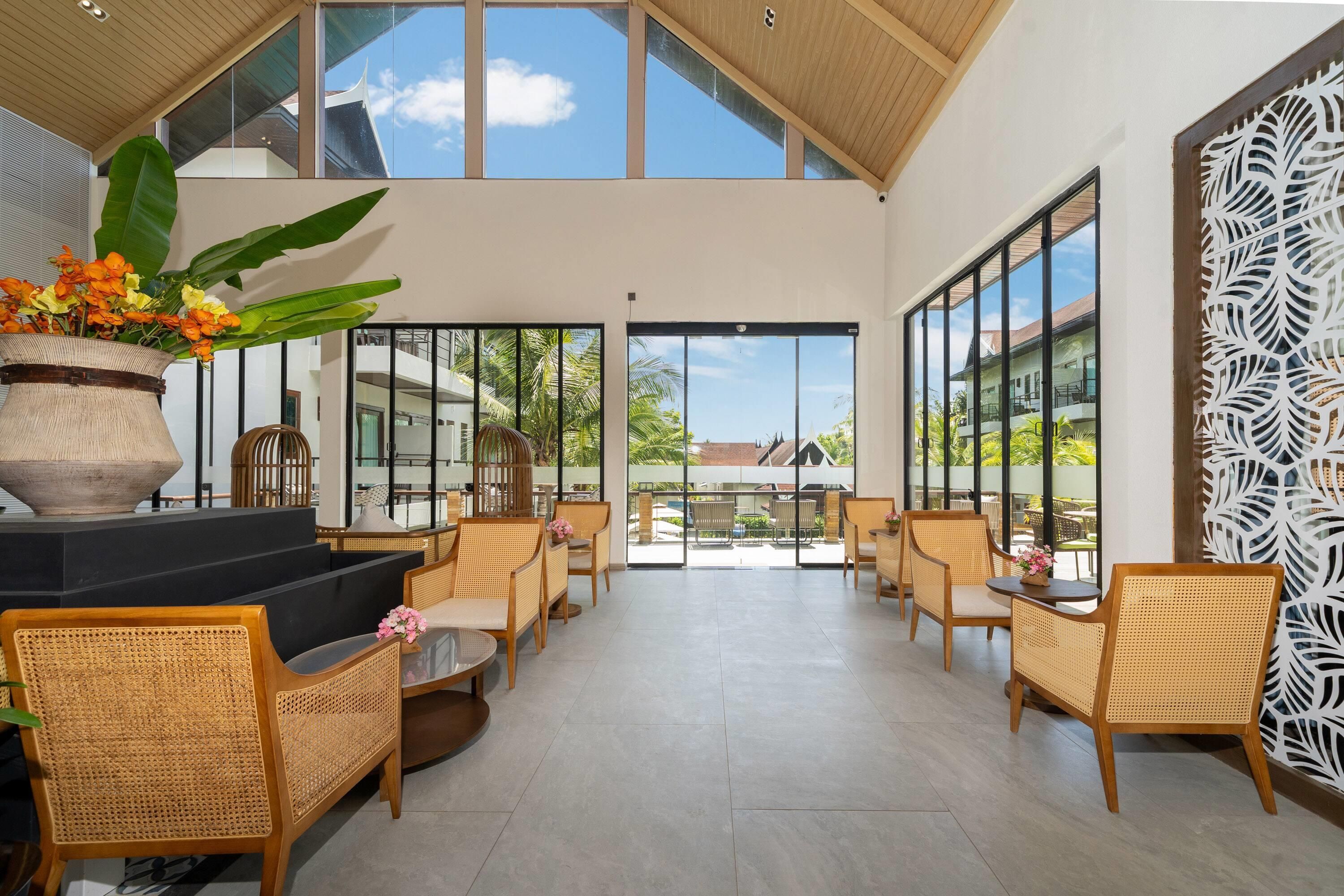 Un espacio interior amplio con techos altos y ventanas grandes, con mobiliario de mimbre y un elemento decorativo central.