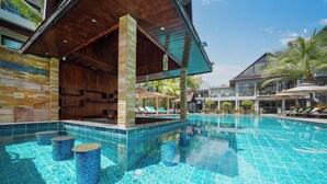 Piscina com espreguiçadeiras e área de estar coberta.
