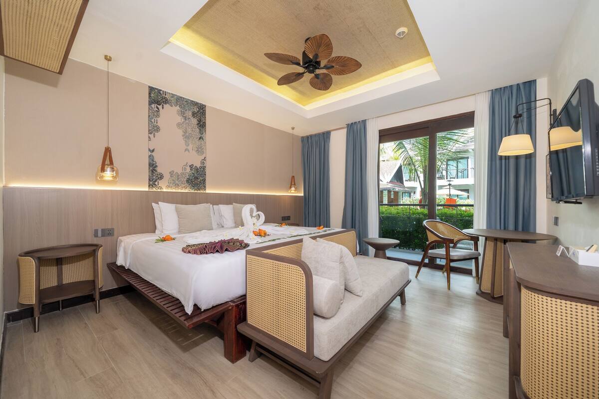 Una habitación de hotel moderna con una cama grande, un sofá, un escritorio y un ventilador de techo.