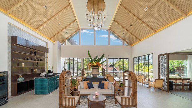 Uma sala de estar ampla com pé direito alto, um candelabro, um sofá com almofadas, uma mesa de centro e uma lareira.