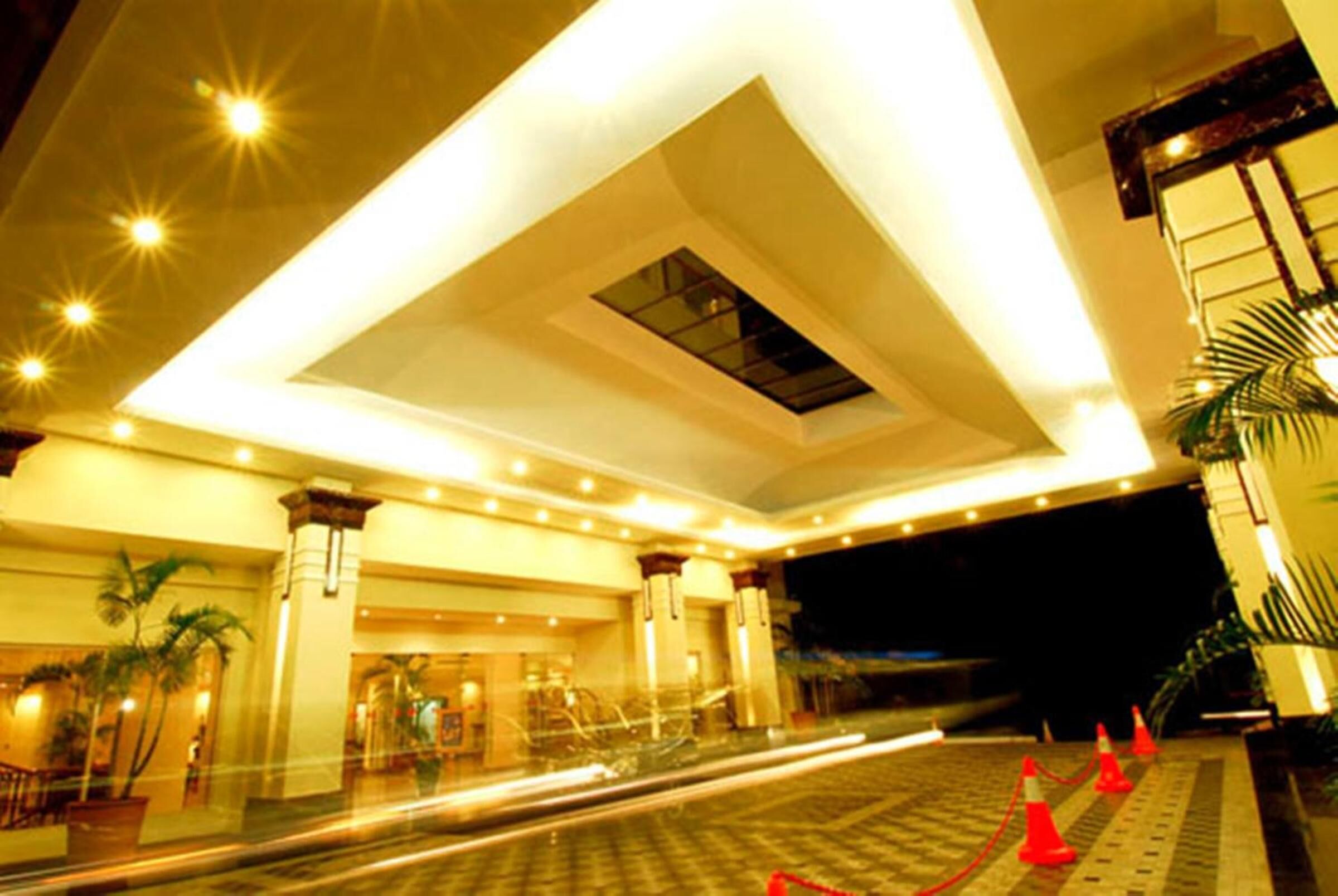 Un vestíbulo de hotel con un espacio amplio y abierto, un tragaluz central y una escalera que conduce a los pisos superiores.