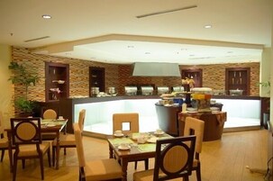 Un restaurante con un mostrador central, sillas de madera y una pared con diseño de piedra.