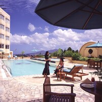 Un área junto a la piscina con sillones, una mesa y sombrillas.