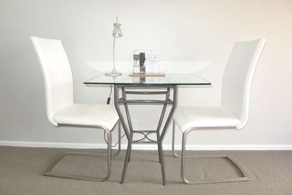 A modern, minimalist room with a glass table and two white chairs.