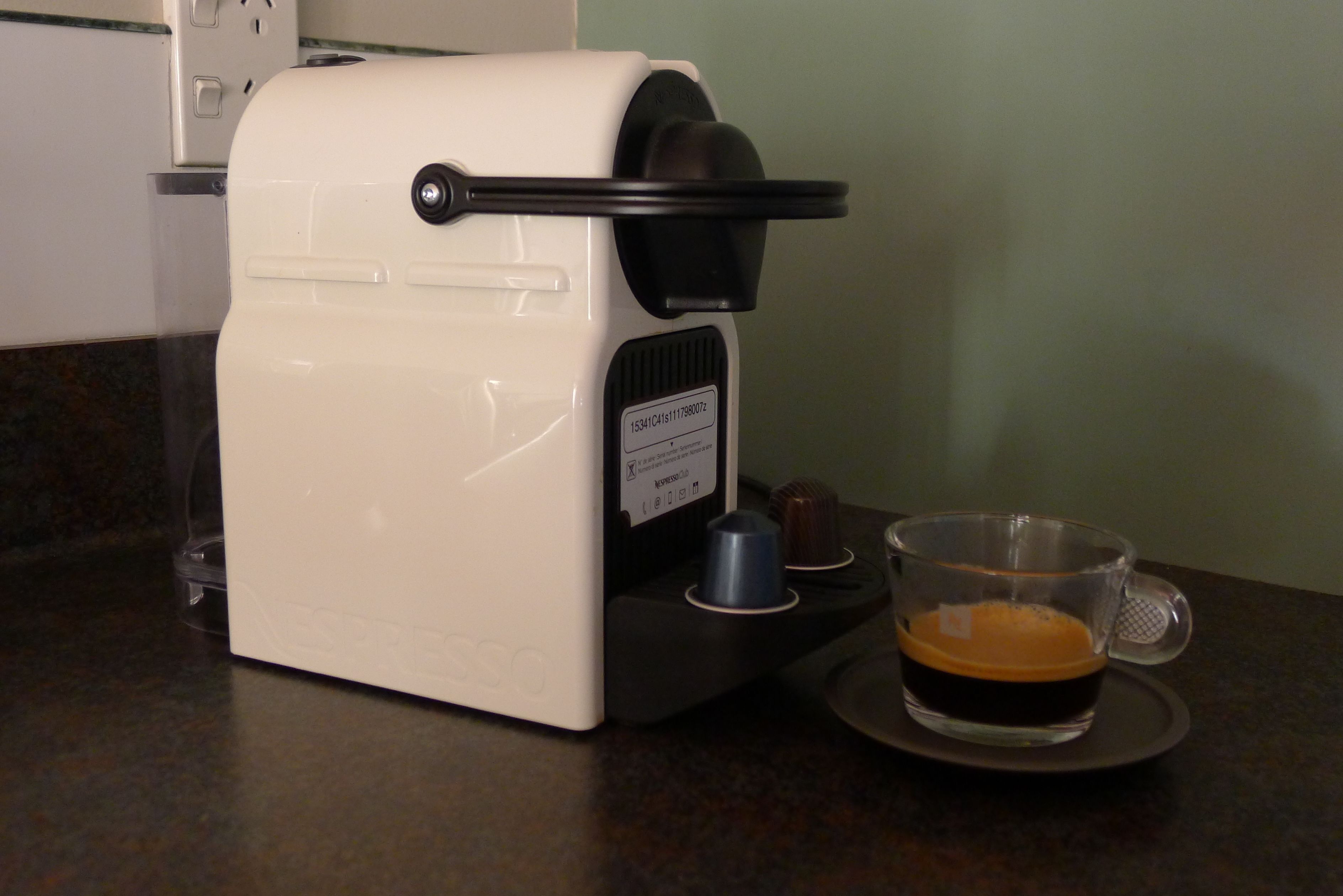 Una cafetera con una taza de café sobre una bandeja.
