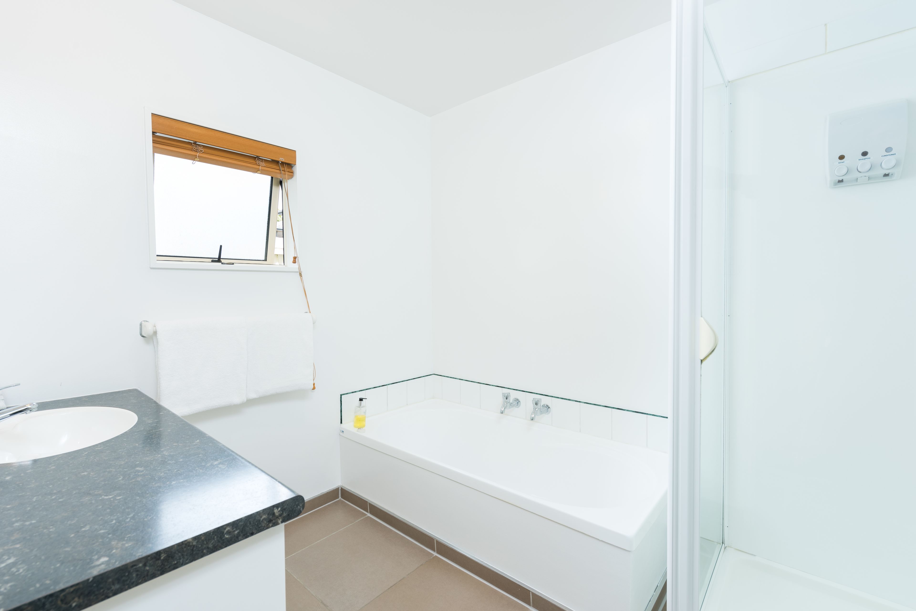 A modern bathroom with a white sink, a glass-enclosed bathtub, and a shower area.