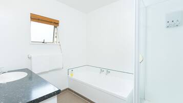A modern bathroom with a white sink, a glass-enclosed bathtub, and a shower area.