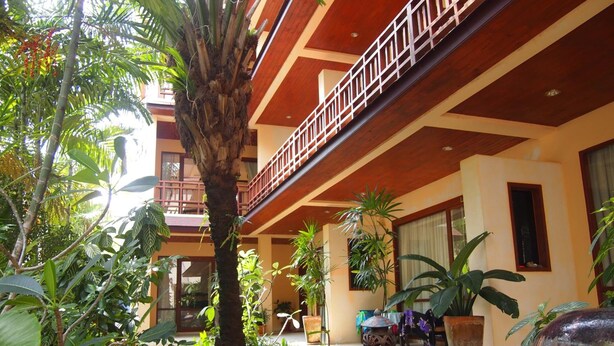 A courtyard with a palm tree, potted plants, and a staircase leading to an upper level. - Summer Inn (Koh Samui)