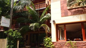 A two-story building with a balcony, a sign for 'Summer Inn', and a stone wall with plants. - Summer Inn (Koh Samui)