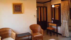 A room with two wicker chairs, a small table, a desk with a mirror, and an air conditioning unit on the wall. - Summer Inn (Koh Samui)