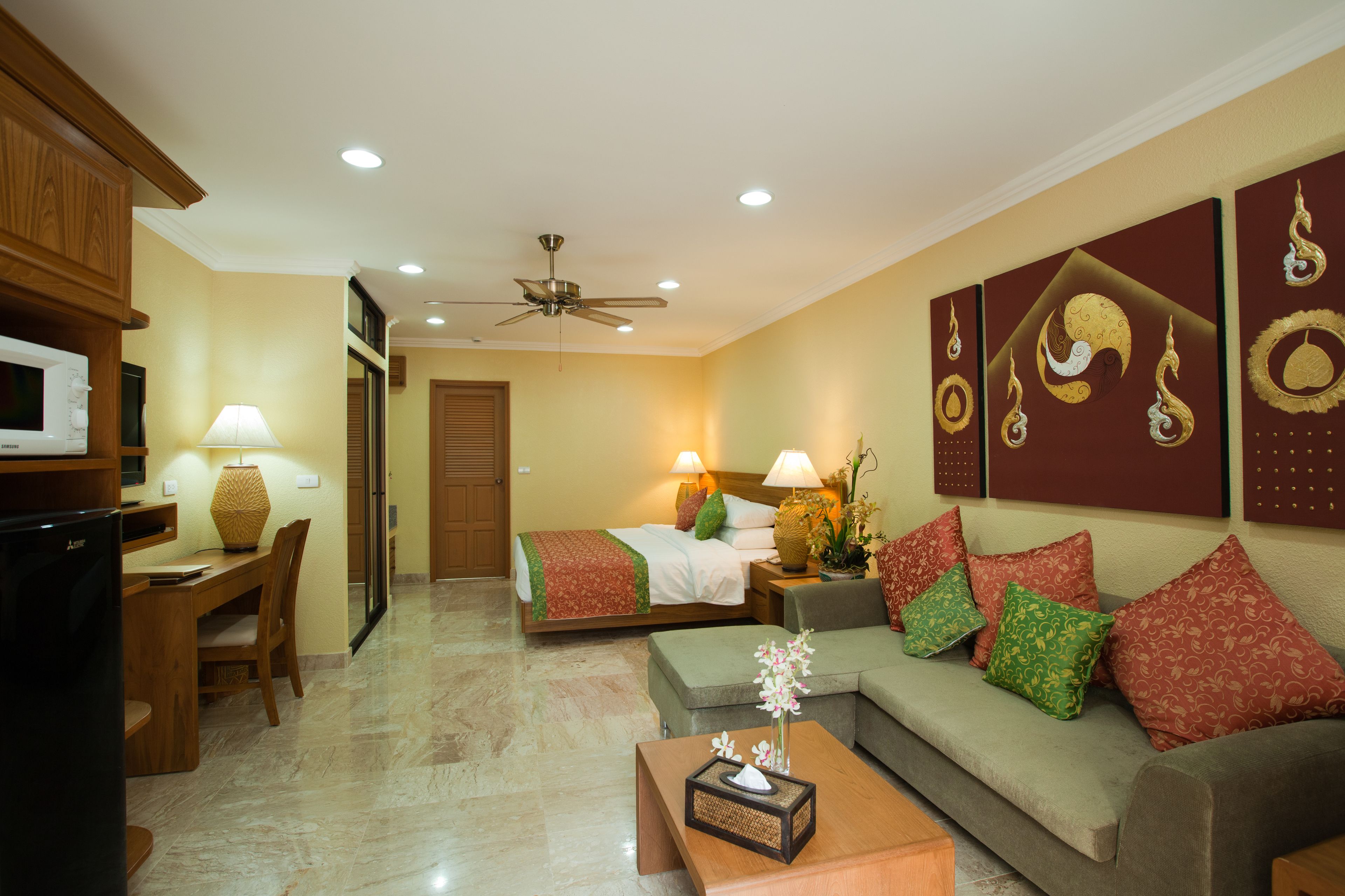 A hotel room with a bed, a sofa, a dining area, and a TV.