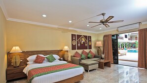 Une chambre d’hôtel avec un grand lit, deux tables de chevet, un ventilateur de plafond et une vue sur l’espace extérieur de la piscine.