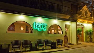Un café y bar con mesas al aire libre y un letrero de neón.