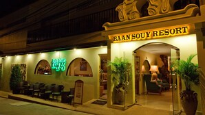L’extérieur du Baan Souy Resort se distingue par son entrée imposante, son espace détente et un panneau lumineux au néon.
