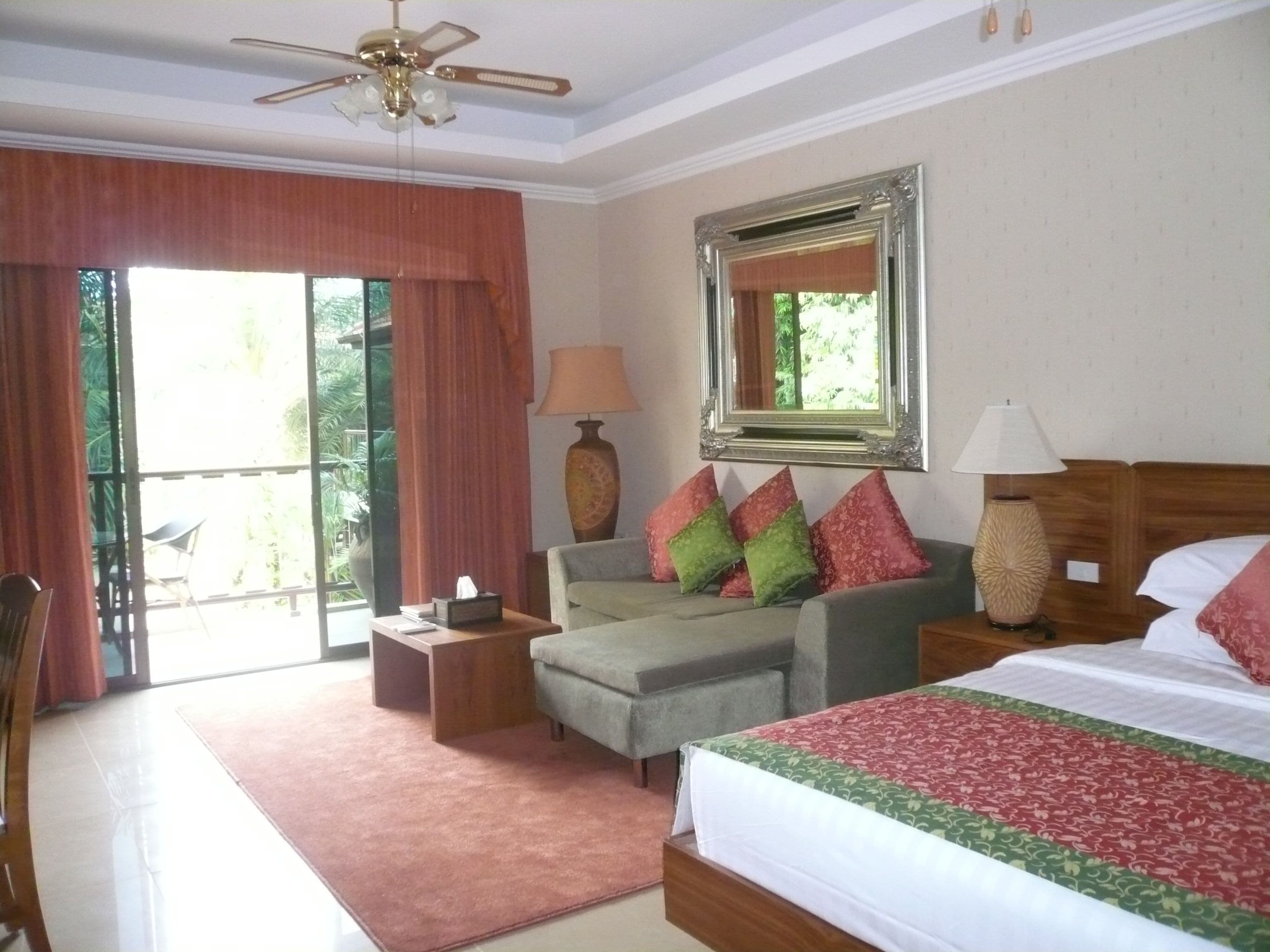 Ein Hotelzimmer mit einem Bett, einer Couch, einem Tisch, einer Lampe und einem Deckenventilator.
