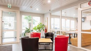 A modern hotel lobby with a seating area, large windows, and a fire extinguisher.