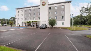 Un hotel tipo bed and breakfast con diseño moderno, que cuenta con una entrada central y un área de estacionamiento.